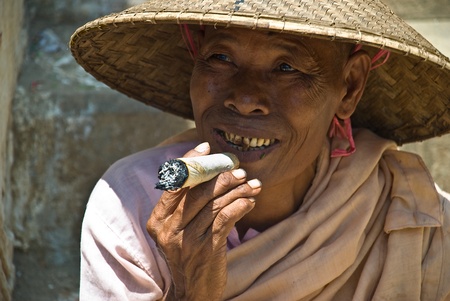 MINGUN, MYANMAR-AUGUST 17, 2007: unidentified nun smoking a big cheroot in Mingun, near Mandalay, August 17, 2007. A cheroot is a cigar made principally by dried fruits and little bit of tobaccoのeditorial素材