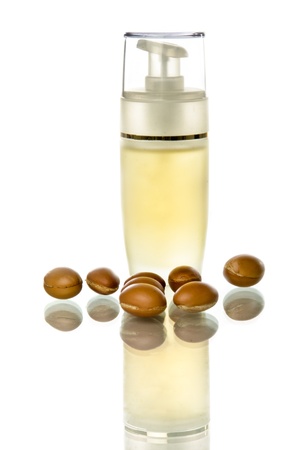 Bottle of argan oil with fruits on a white background and reflectionの写真素材