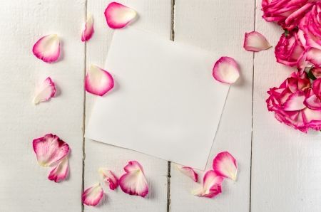 white paper on wooden  tabletop with rose petals and flowersの写真素材