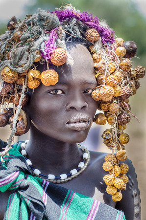 JINKA, ETHIOPIA - 10 August: unidentified beautiful girl from Mursi tribe in Mago National Park, Jinka, on 10 august 2014. Mursi people usully paint their bodies and use many natural ornaments like leaves and fruitsのeditorial素材