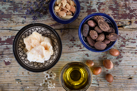 Shea butter and nuts and argan fruits and oil on a wooden tableの写真素材