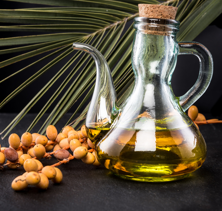 Bottle of palm oil and palm fruits on black backgroundの写真素材
