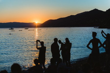 Sunset on the beach of Camogli with silhouette of people enjoyng the vacationの写真素材