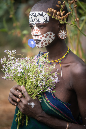 KIBISH, ETHIOPIA - AUGUST 22, 2018: unidentified woman from Surmi tribe, with flower decorations. Surmi are also called Suri or Surma and live in villages in the south wester part of Ethiopiaのeditorial素材