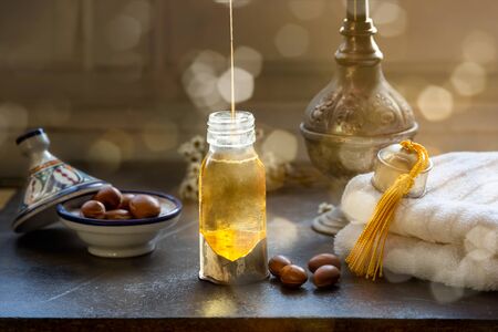 Glass bottle of Argan oil on a table with argan fruitsの写真素材