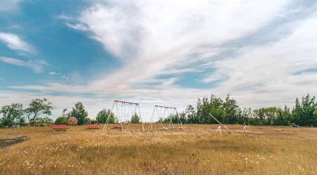 small park with games for children in the middle of the field under a sky with cloudsの写真素材