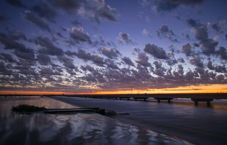 long exposure photograph with silk effect on the river with a bridge in the background under a dawnの写真素材