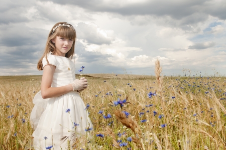 girl wearing first communion dress among the flowers and spikesの写真素材