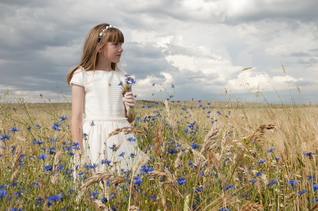 girl wearing first communion dress among the flowers and spikesの写真素材
