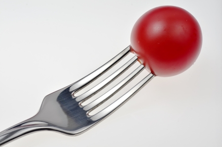 cherry tomato stuck with fork on white backgroundの写真素材