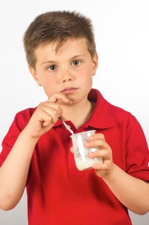photograph of a child eating yogurt over white backgroundの写真素材