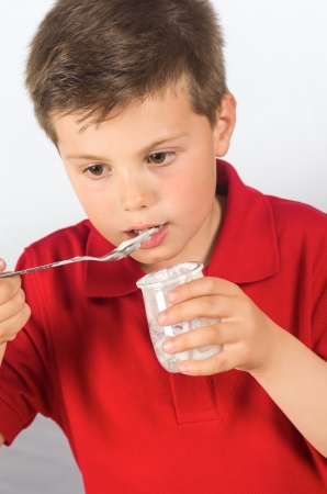 photograph of a child eating yogurt over white backgroundの写真素材