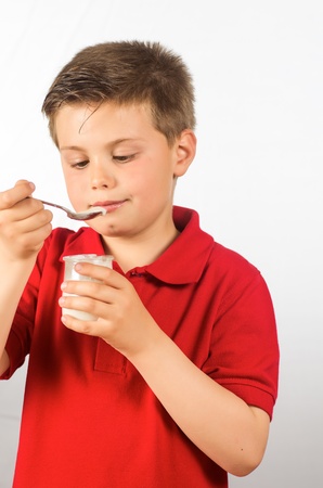 photograph of a child eating yogurt over white backgroundの写真素材