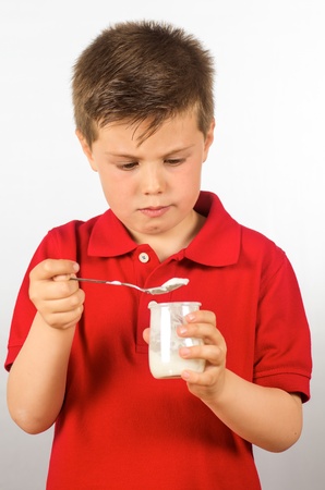 photograph of a child eating yogurt over white backgroundの写真素材