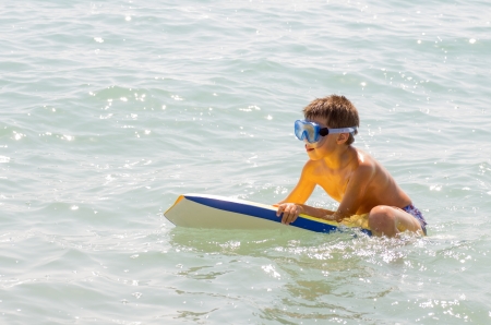 photograph of a child taking his first surfing lessons on the beachの写真素材