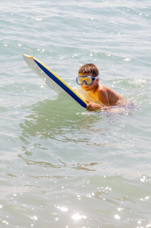 photograph of a child taking his first surfing lessons on the beachの写真素材