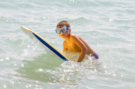 photograph of a child taking his first surfing lessons on the beachの写真素材