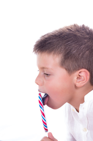 child enjoying a tasty lollipop isolated on whiteの写真素材