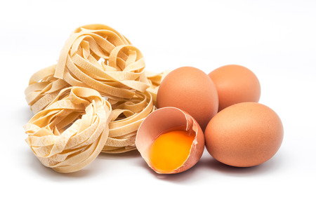 photograph of three eggs and half with several nests of pastaの写真素材
