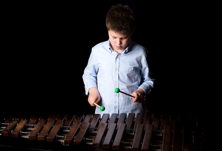 Boy playing on xylophone. Black background, close-upの写真素材