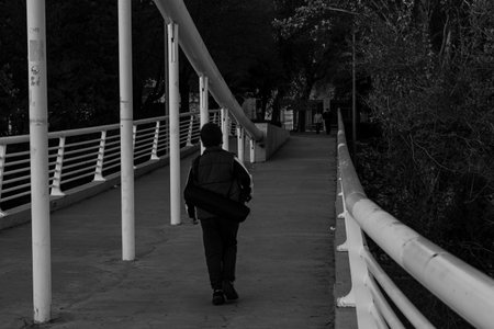 A child carries a bag as they walk along a peaceful pathway lined with trees during the late afternoon.の写真素材