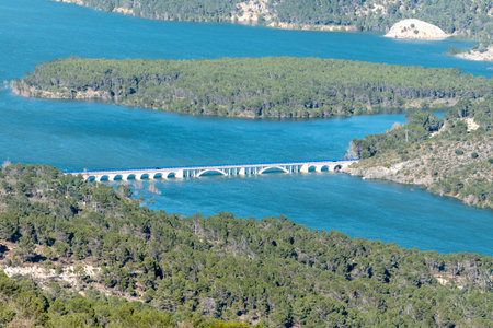 Beautiful view of a blue bridge over turquoise water surrounded by green trees in a serene landscapeの写真素材