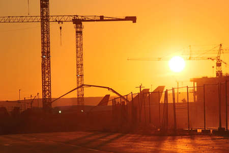 Planes and cranes at Frankfurt Airport during a sunsetのeditorial素材