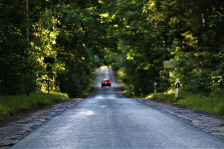 Asphalt road after the rain in the evening with a car in the background