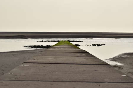 Stone pier by the sea with a sandbank in the background