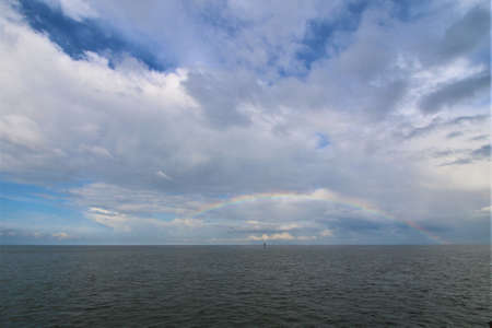 Rainbow above the north sea against a blue sky with clouds