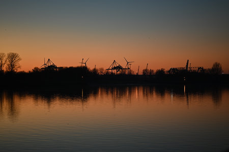 Evening mood besides a river against a containerport and sunsetの写真素材