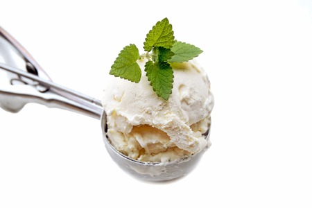 A steel ice cream scoop filled with vanilla ice creamの写真素材