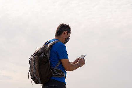 Young girl with backpack looking at her cell phone with white backgroundの写真素材