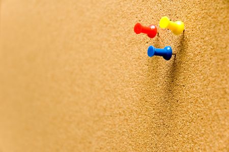 a cork board with three tacks on it