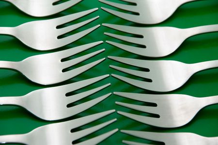 arrangement of silverware forks over green backgroundの写真素材
