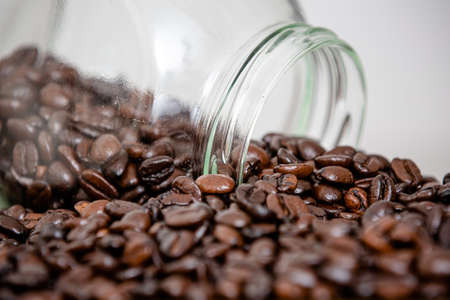 Glass with red lid pouring over the table in beans coffee powder straight from the farm.の写真素材