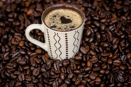 Cup with coffee turned on the table straight from the farm in beans roasted coffee beans hot and...