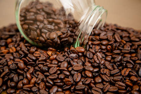 Glass with red lid pouring over the table in beans coffee powder straight from the farm.