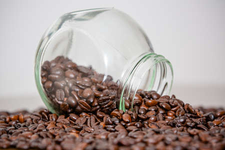 Glass with red lid pouring over the table in beans coffee powder straight from the farm.