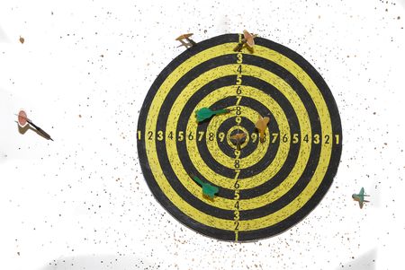 Target with darts against a white wall full of holesの写真素材