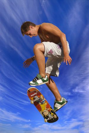 Boy jumping with a skateboard against a blue sky