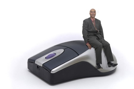 Businessman siting on a mouse isolated in whiteの写真素材