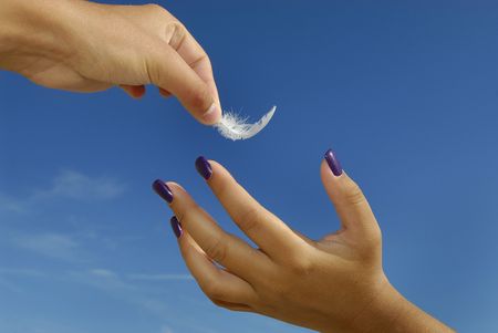 Hand holding a feather over anotherの写真素材