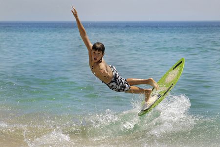 Boy jumping in the air with skimboard in the sea