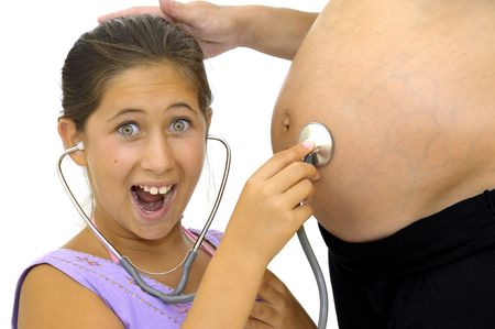 Beautiful young girl listening to pregnant mother's belly with stethoscope and happy faceの写真素材