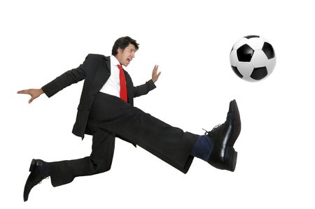 Businessman in a acrobatic pose kicking a soccer ball  isolated in whiteの写真素材