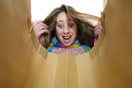 Beautiful young girl looking inside colorful bag isolated in whiteの写真素材