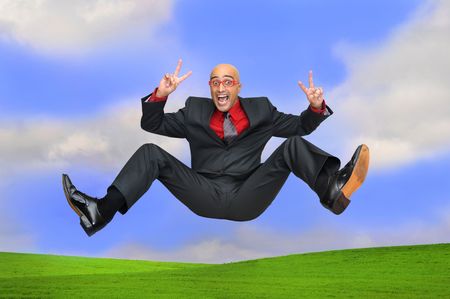 Happy businessman jumping outdoors in a green fieldの写真素材