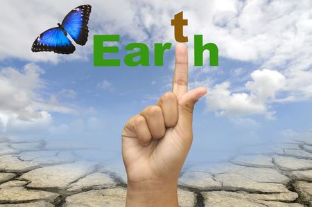 Hand with earth word and butterfly over a dry soil and sky background