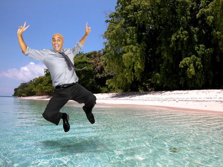 Happy businessman jumping in a tropical background